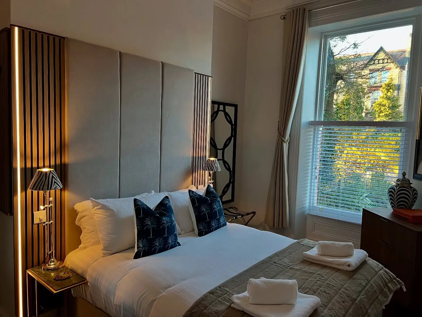 Bedroom with a tall panelled headboard and slatted wall
