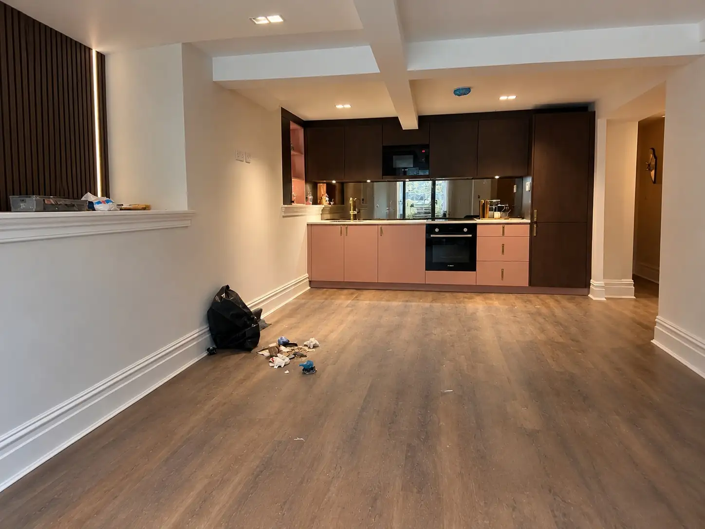 Before: the same room empty, with a bare floor and the fitted kitchen