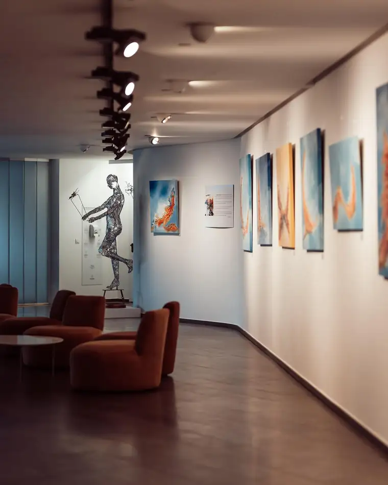 The gallery corridor with a sculpture and paintings along the wall