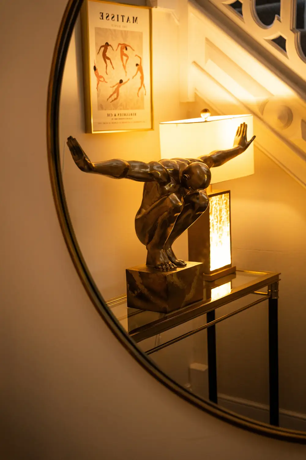 Bronze figure sculpture and lamp reflected in a round mirror