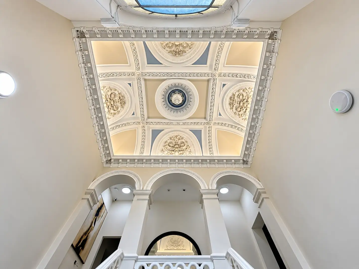 Ornate plaster ceiling and skylight above the stairwell arches