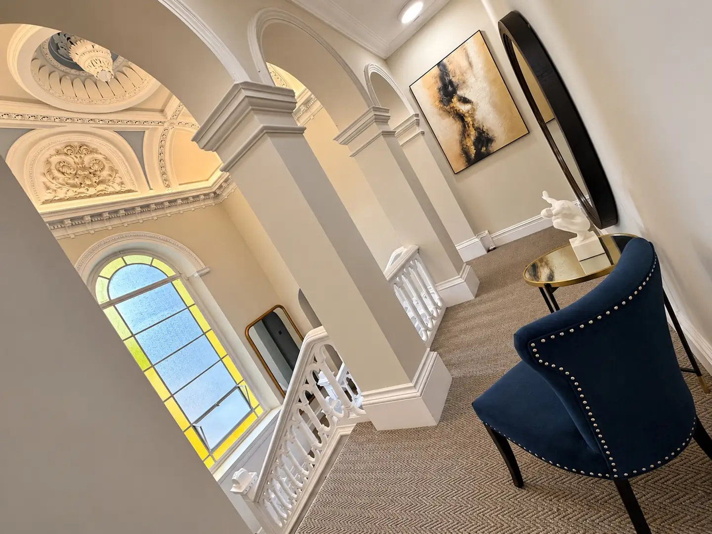 Landing arches, stained glass window and navy studded chair