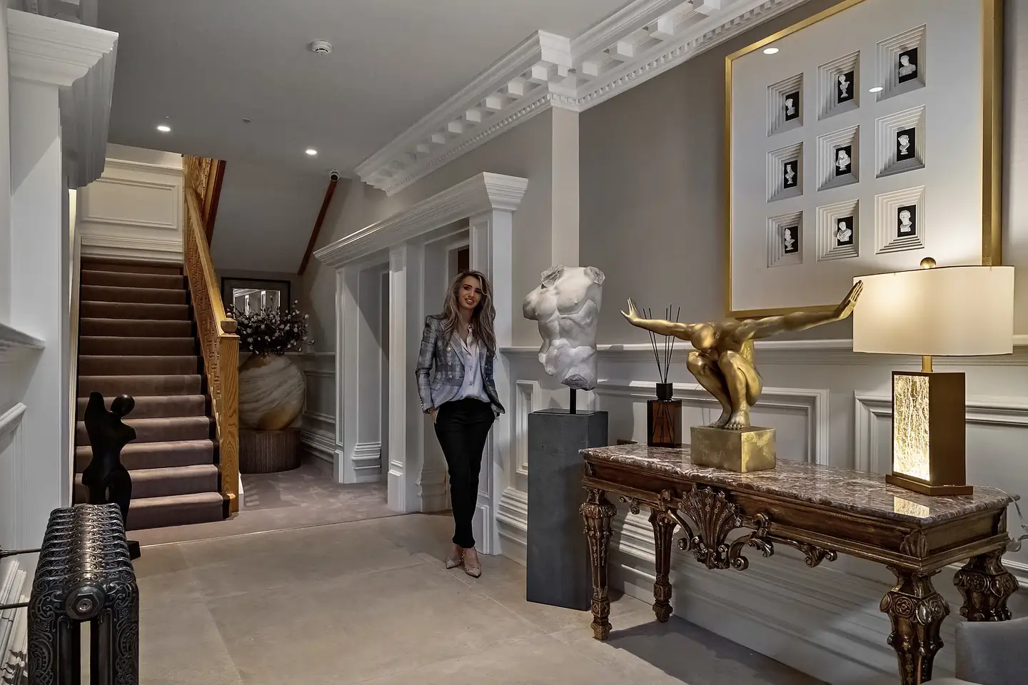 Dannielle in the lobby beside the marble torso, with the staircase behind